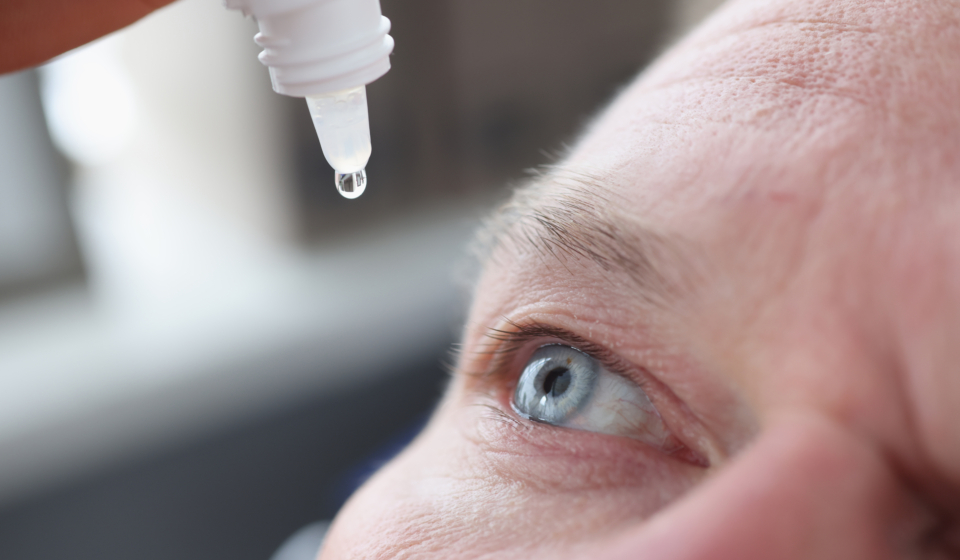 Young caucasian man shot in head with eye drops. Unhealthy man with blurred vision treats eyes concept